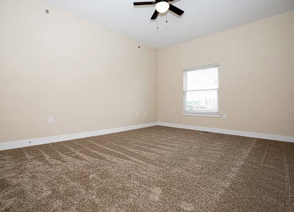 A room with a carpeted floor and a ceiling fan.