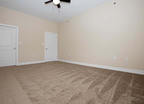 A room with a carpeted floor and a ceiling fan.