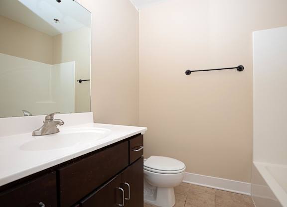 A white toilet sits in a bathroom with a white sink and a white bathtub.