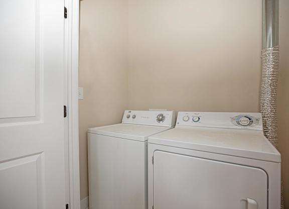Two white washing machines in a small laundry room.