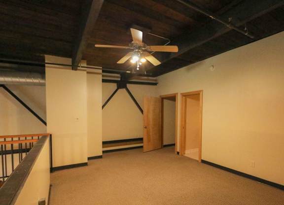 A room with a ceiling fan and a balcony.