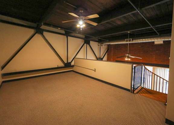 A room with a ceiling fan and a carpeted floor.