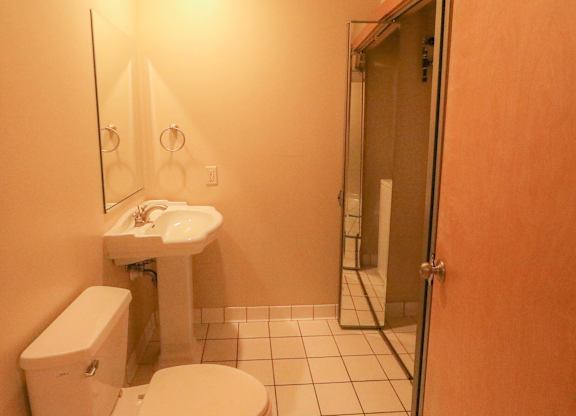 A bathroom with a toilet, sink, and mirror.