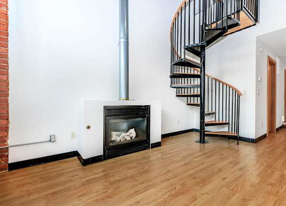 A black spiral staircase in a room with a fireplace.