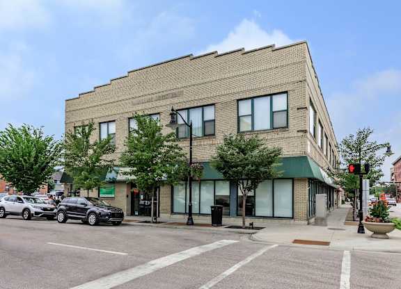 A street view of a building with cars parked in front.