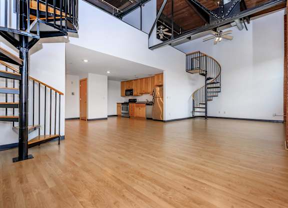 A large open space with a spiral staircase and wooden floors.