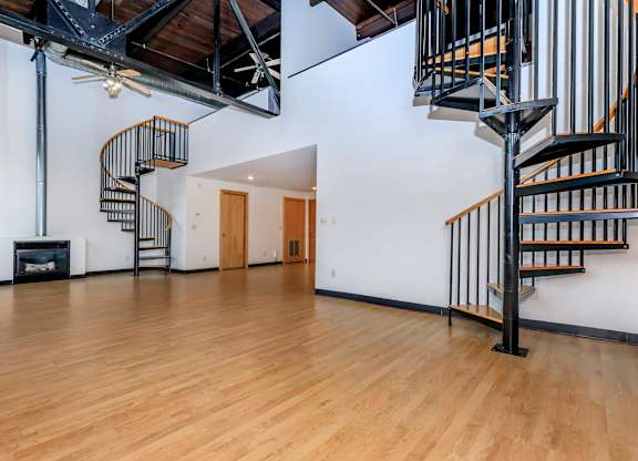 A large open room with a spiral staircase and a fireplace.