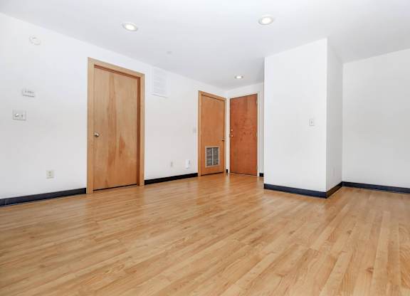 A room with wooden floors and two doors.