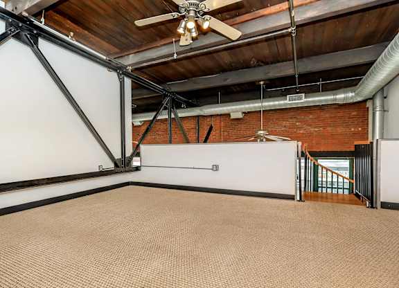 A room with a ceiling fan and a brick wall.