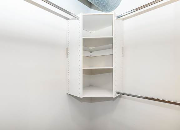 A white open cabinet with shelves and a blue object hanging from the ceiling.