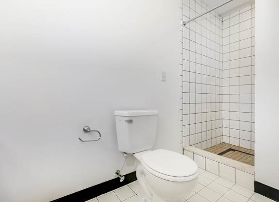A white toilet in a bathroom with a white tiled wall and floor.