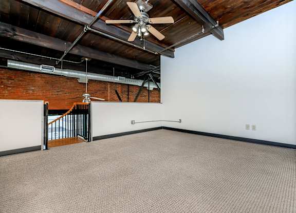 A room with a ceiling fan and a staircase.