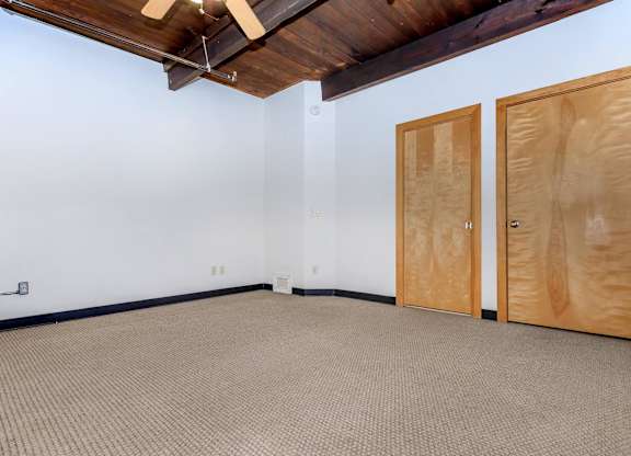 A room with a carpeted floor and two wooden doors.