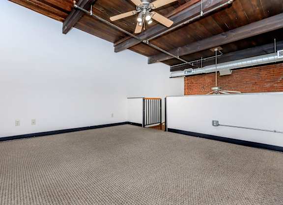 A room with a ceiling fan and a brick wall.