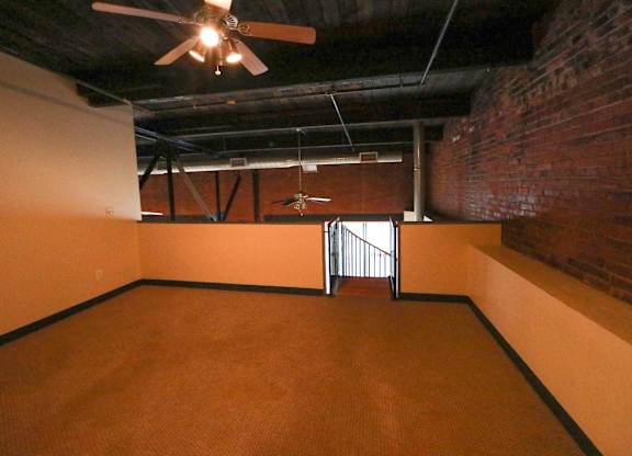 A room with a ceiling fan and a door with a metal railing.