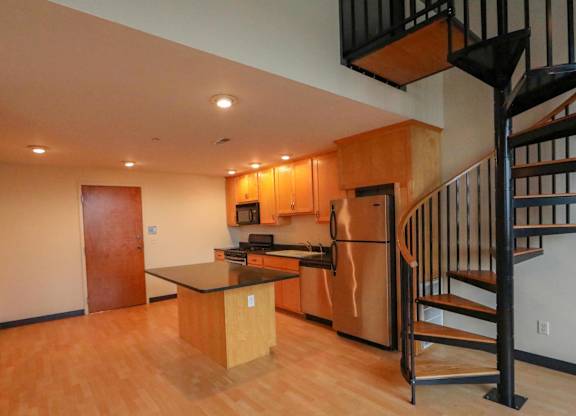 A kitchen with a black staircase on the right.
