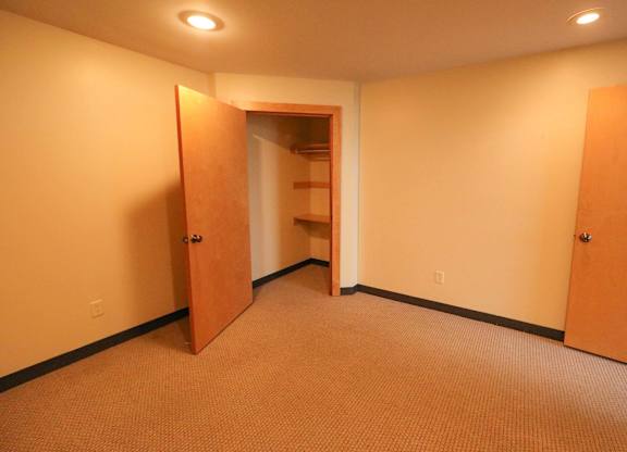 A hallway with a carpeted floor and two open doors.