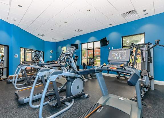 A gym with treadmills, elliptical machines, and a weight machine.