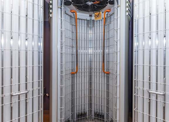 A wall of white panels with orange pipes hanging from the ceiling.