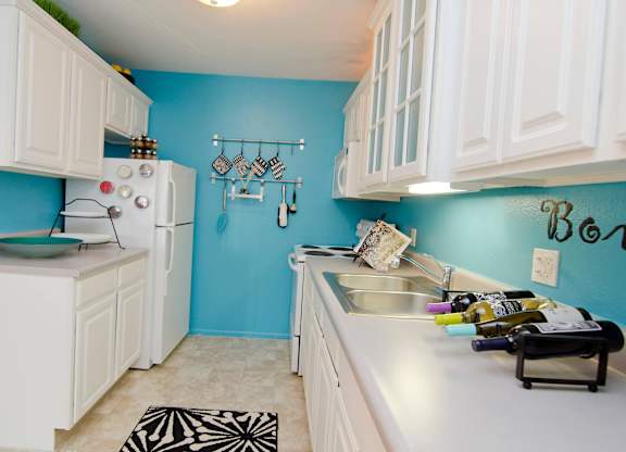 A kitchen with white cabinets and a blue wall.