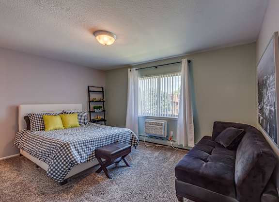 A bedroom with a bed, chair, and window.