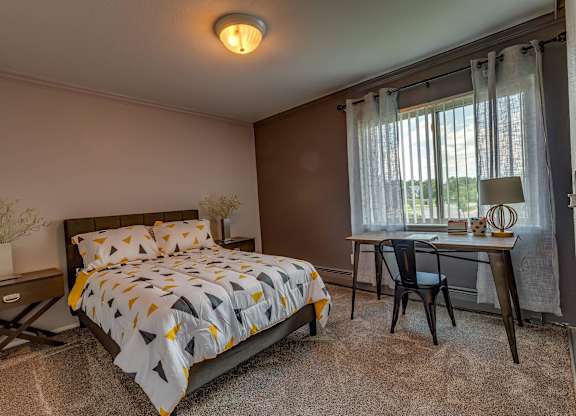 A bedroom with a bed, desk, and chair.