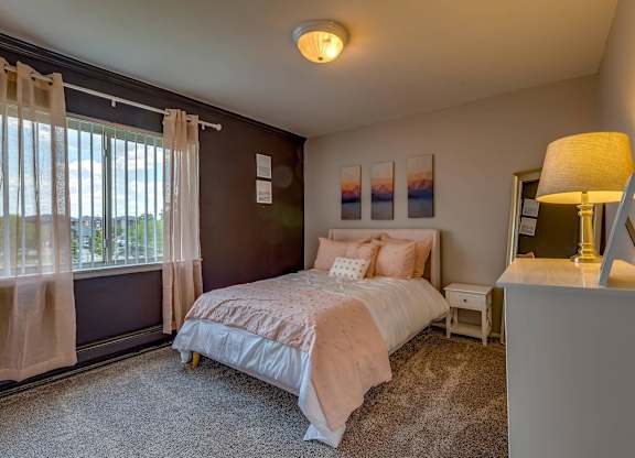 A bedroom with a large bed and a window with curtains.