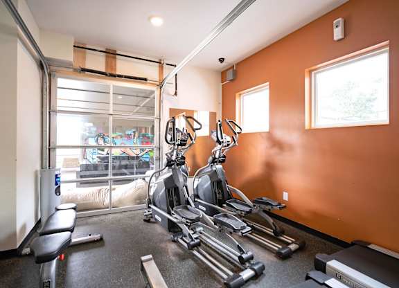A gym with orange walls and a row of treadmills.