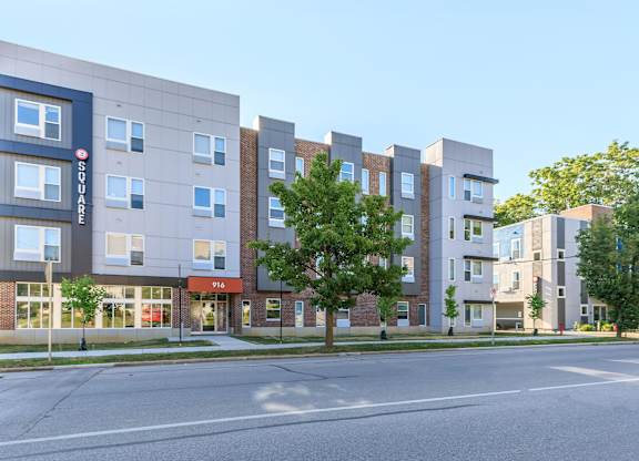 A modern apartment building with a blue and white sign on the left side.