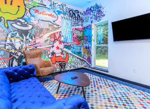 A room with a blue couch and a wall covered in graffiti.