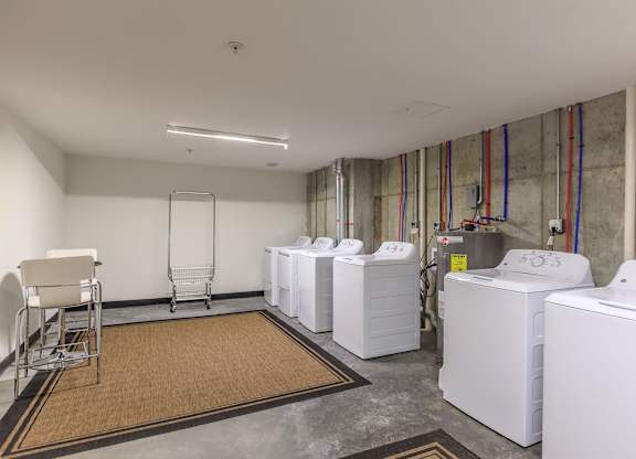 A laundry room with a washer and dryer on the right and a chair on the left.