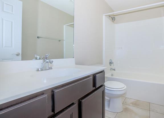 A white sink with a silver faucet and a white toilet in a bathroom.