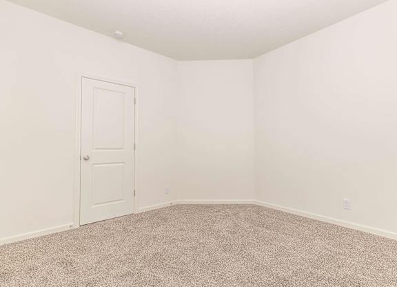 A room with a carpeted floor and a white door.
