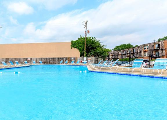 A large swimming pool with blue water and lounge chairs.