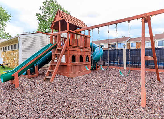 A playground with a green slide and a red wooden structure.