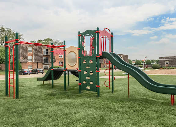 A playground with a green slide and red and green play structure.