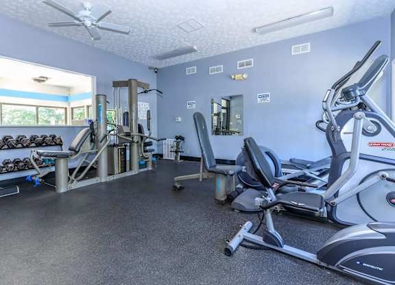 A gym with a variety of equipment including treadmills, weights, and exercise machines.