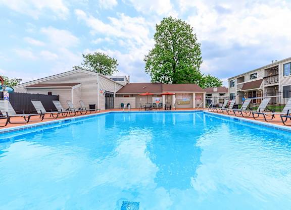A swimming pool in a residential area with a blue sky and clouds.