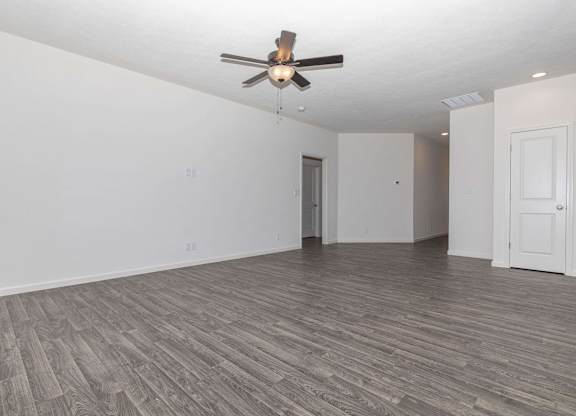 A room with a ceiling fan and wood flooring.