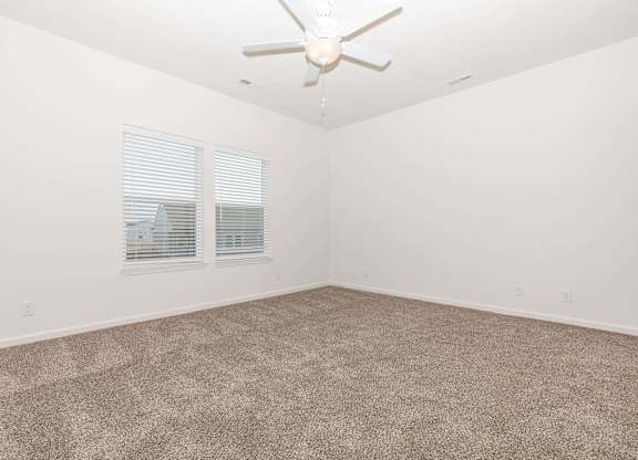 A room with a ceiling fan and carpeted floor.