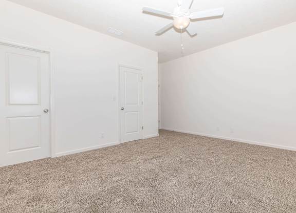 A room with a ceiling fan and carpeted floor.