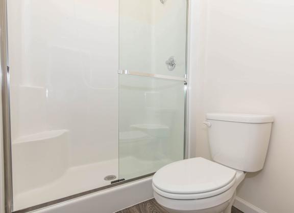 A white toilet sits next to a glass shower stall.