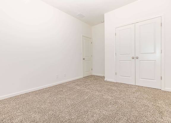 A room with carpeted floor and two doors.