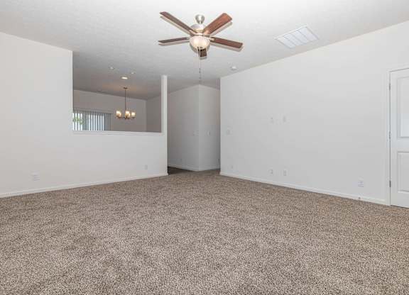 A room with a ceiling fan and carpeted floor.