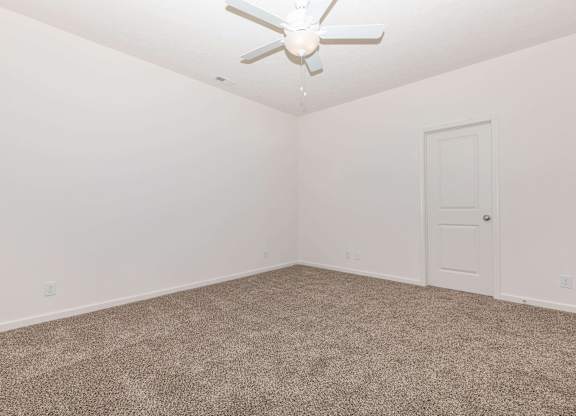 A room with a ceiling fan and carpeted floor.