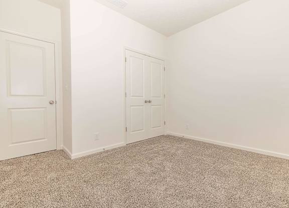 A room with two doors and carpeted floor.