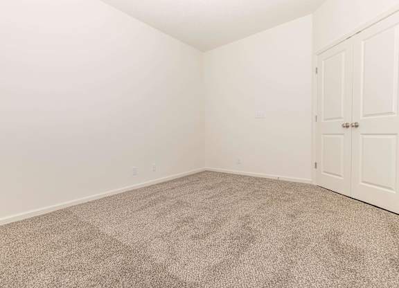 A room with a carpeted floor and a white door.