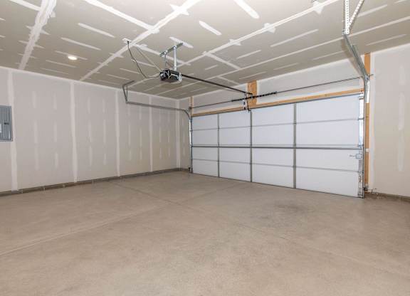 A spacious garage with a white ceiling and a white garage door.