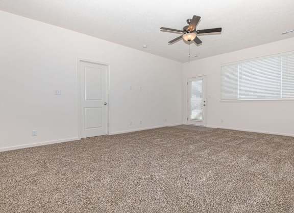 A room with a ceiling fan and carpeted floor.