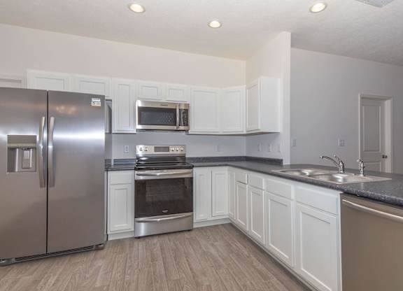 A kitchen with a stainless steel refrigerator, microwave, oven, and sink.